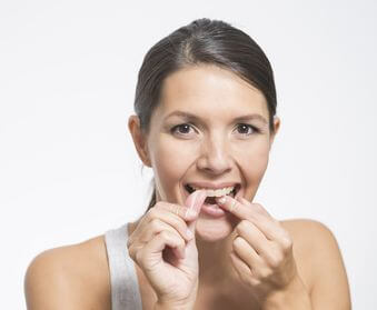 Frau benutzt Zahnseide